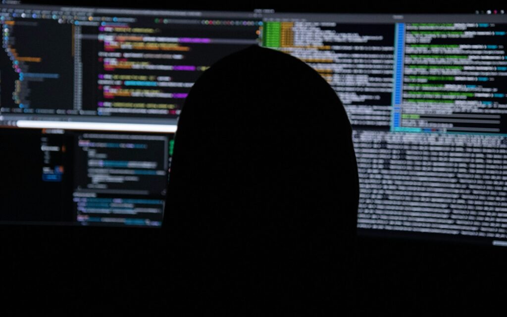 Person vor mehreren Monitoren mit Code richtet ein Cookie-Banner auf der Website ein