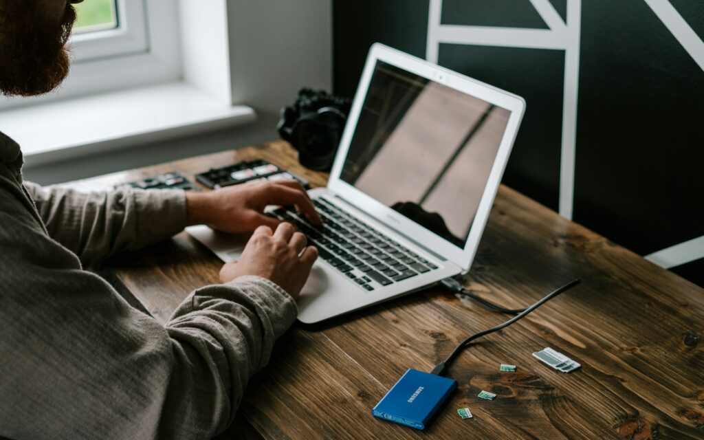 Mitarbeiter sichert Daten am Laptop auf eine externe SSD für das 3-2-1-Backup