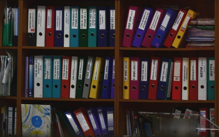 Bunte Ordner im Büroregal: Aufbewahrungsfristen bestimmen, wie lange Unterlagen archiviert werden