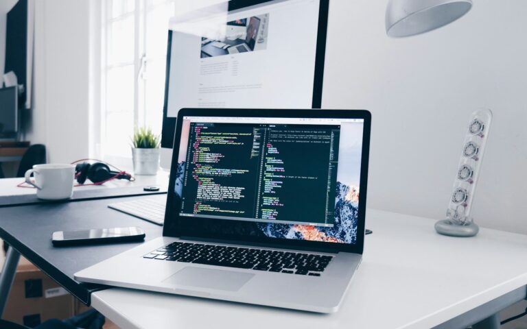 Laptop mit Quellcode auf dem Schreibtisch, während ein Team die Domain umziehen will