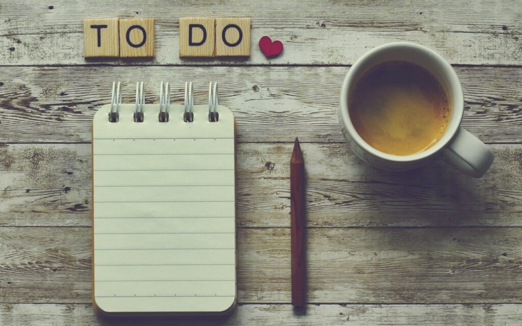 To-do-Liste und Kaffeetasse auf dem Schreibtisch zur Planung mit der Eisenhower-Methode