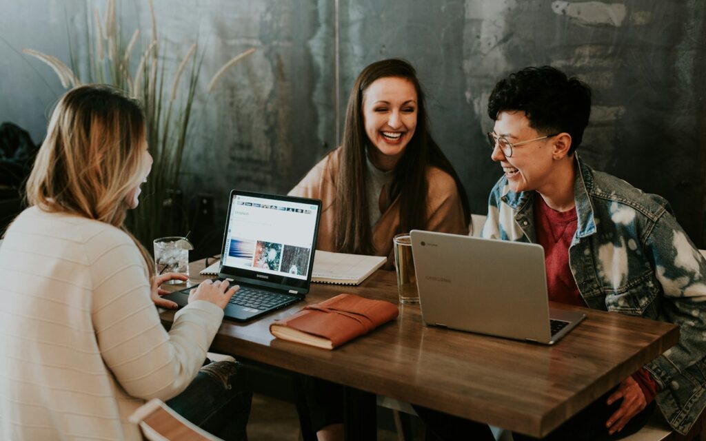 Employer Branding im Team: Drei Kollegen sitzen lachend gemeinsam an einem Tisch