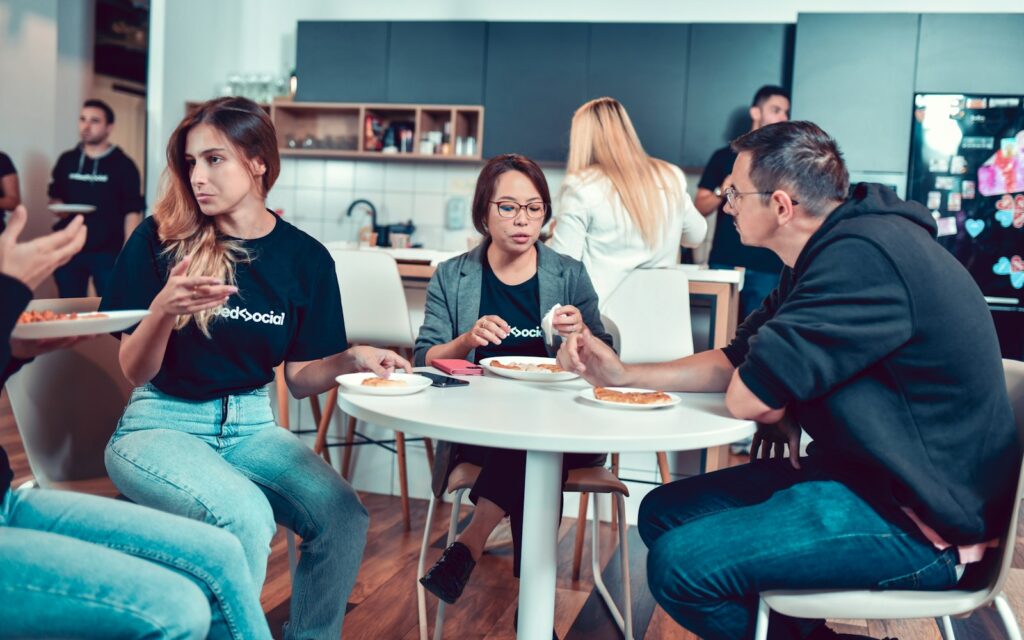 Employer Branding nach innen: Kollegen sitzen gemeinsam beim Essen an einem Tisch
