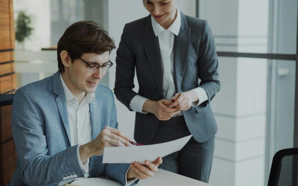 Zwei Geschäftsleute prüfen gemeinsam Rechnungen und Unterlagen für das Factoring