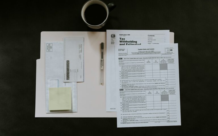 Steuerformulare, Stift und Kaffeetasse auf dunklem Schreibtisch – Fragebogen zur steuerlichen Erfassung vorbereiten