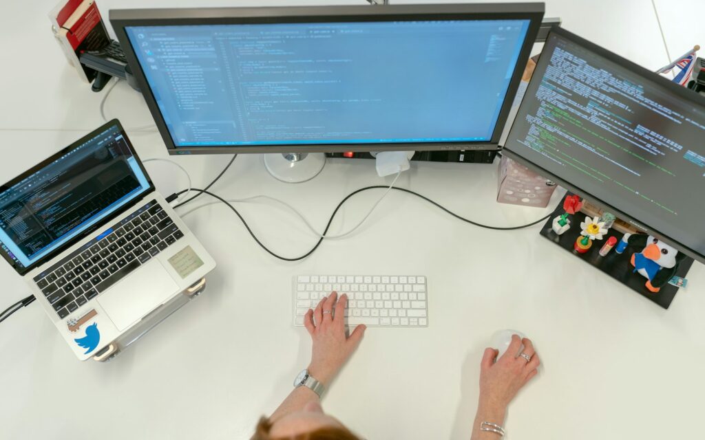 Schreibtisch von oben mit Monitoren und Laptop zur Analyse der Ladezeit einer Website