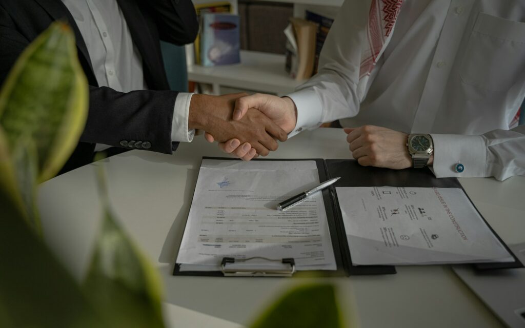 Handschlag über Vertragsunterlagen nach dem Lieferantenvergleich