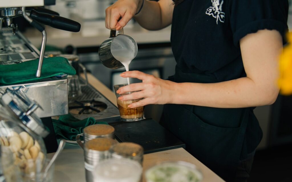 Barista gießt Milch in ein Glas – Aushilfsjob im Café beim Mindestlohn 2027
