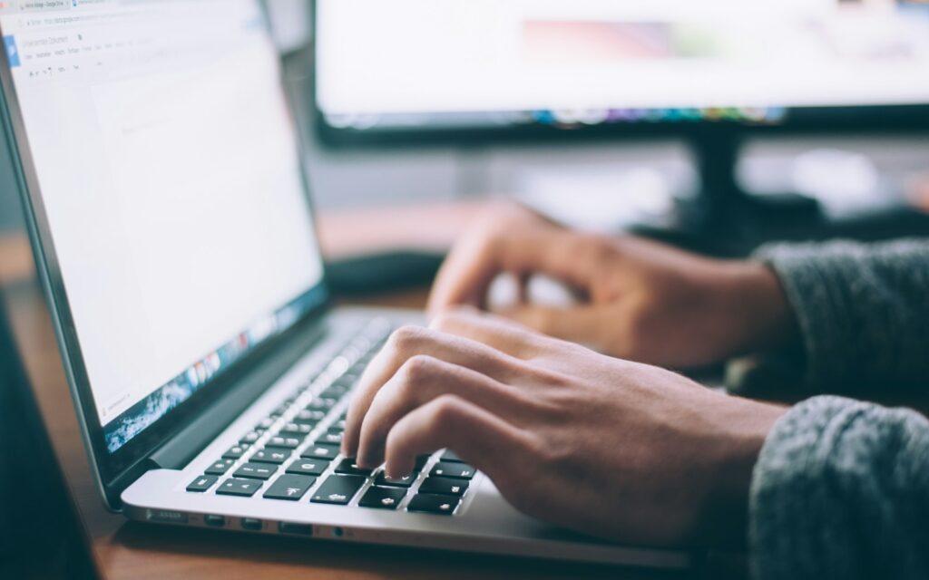 Hände tippen auf einem Laptop: Newsletter-Marketing für kleine und mittlere Unternehmen planen