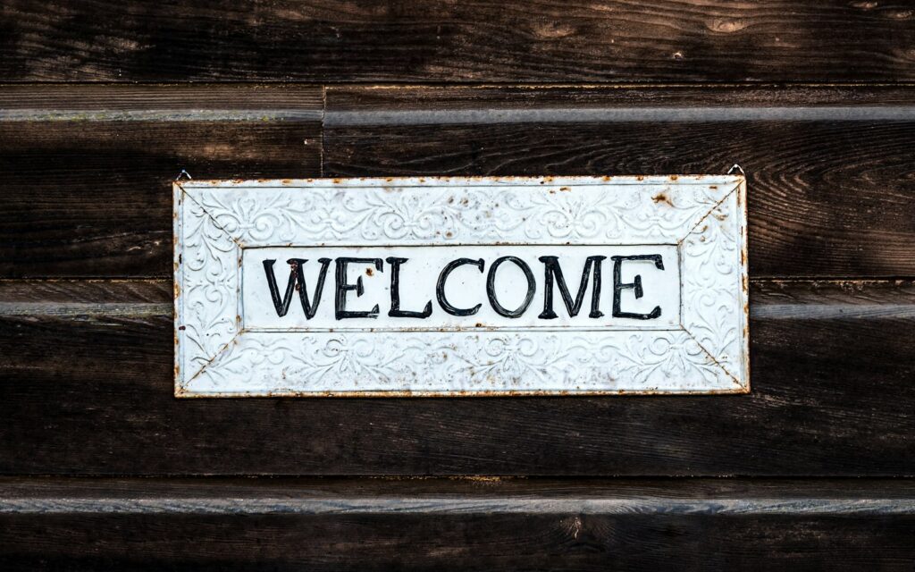 Holzschild mit der Aufschrift Welcome als Symbol für das Onboarding neuer Mitarbeiter