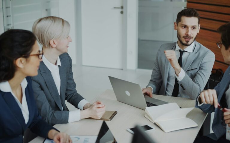 Vier Personen am Besprechungstisch in einem der wöchentlichen Teammeetings