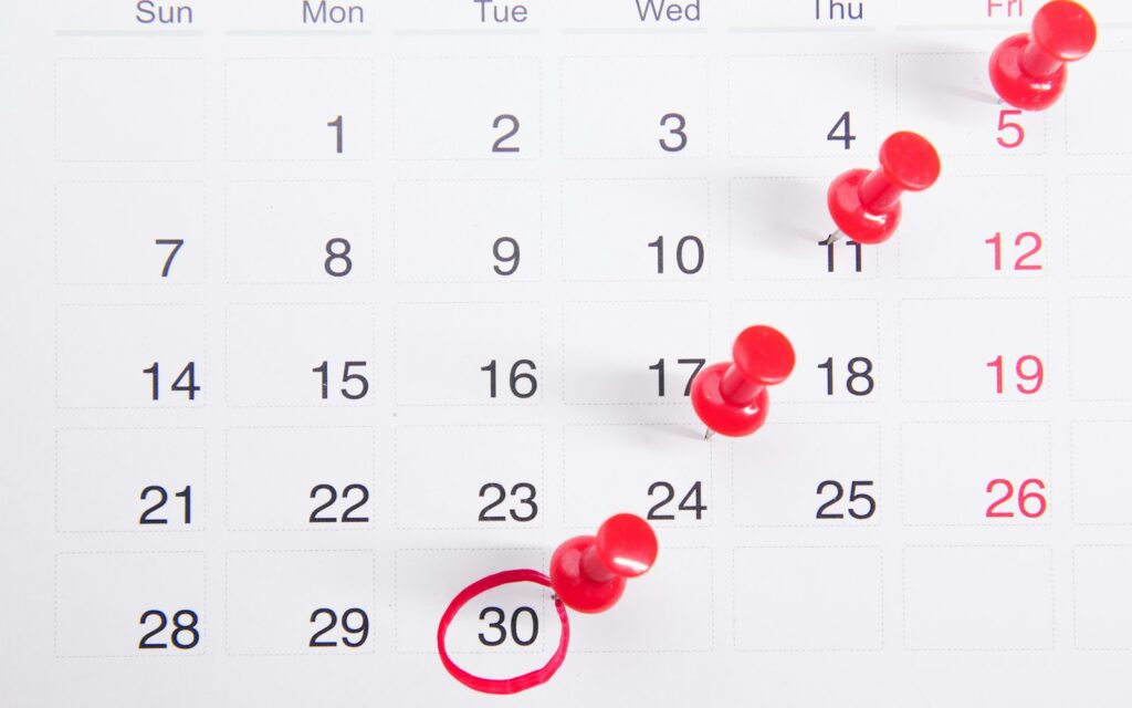 Kalender mit roten Pinnnadeln als Symbol für freie Tage in der Vier-Tage-Woche
