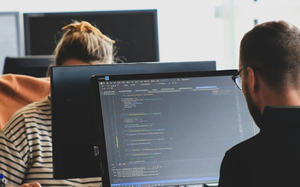 Zwei Entwickler arbeiten an Code auf Monitoren und führen einen Website-Check durch
