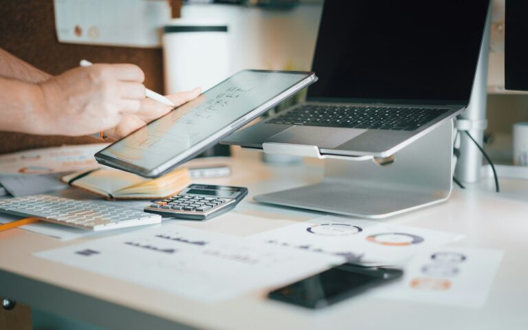 Laptop und Taschenrechner auf einem Schreibtisch zur Kalkulation der Website-Kosten