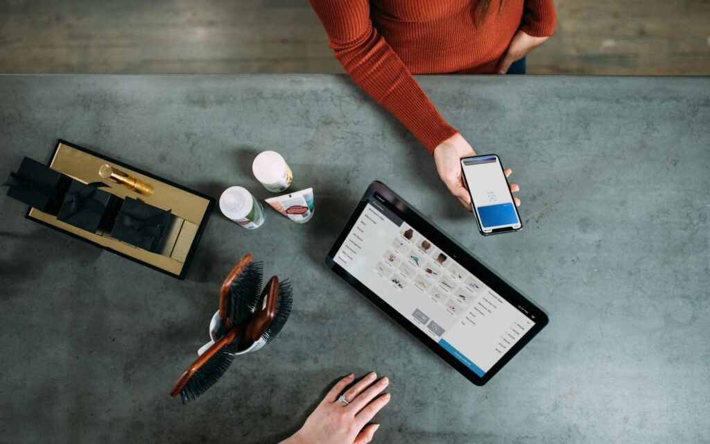 Hand hält Smartphone neben Tablet im Geschäft, um Neuigkeiten im WhatsApp-Kanal zu posten