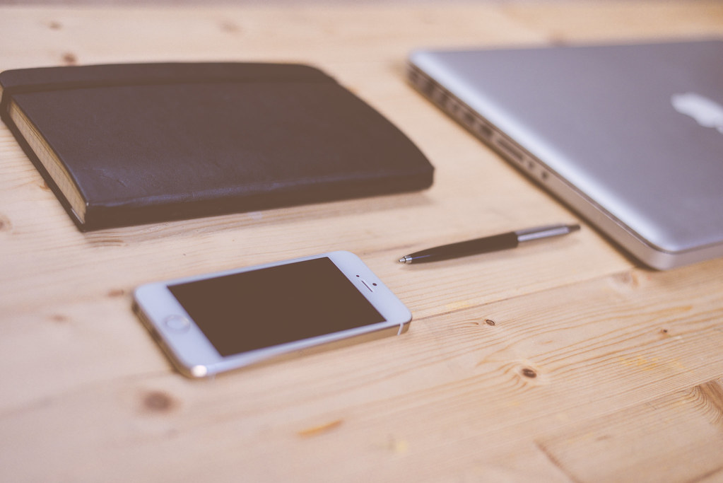 Smartphone neben Laptop und Notizbuch – mit WhatsApp Web am Büro-Arbeitsplatz chatten