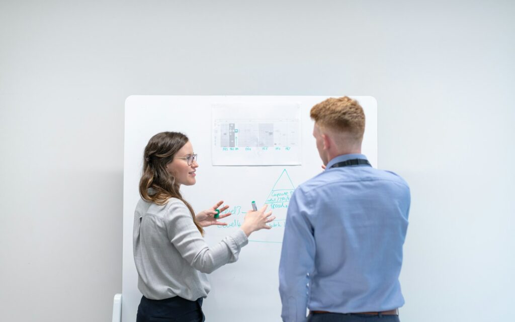 Zwei Kollegen besprechen am Whiteboard, wie sie ihre Zielgruppe definieren